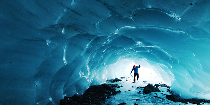 Person entering ice cave blue in color