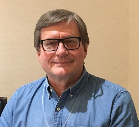 man with short salt and pepper hair and black glasses