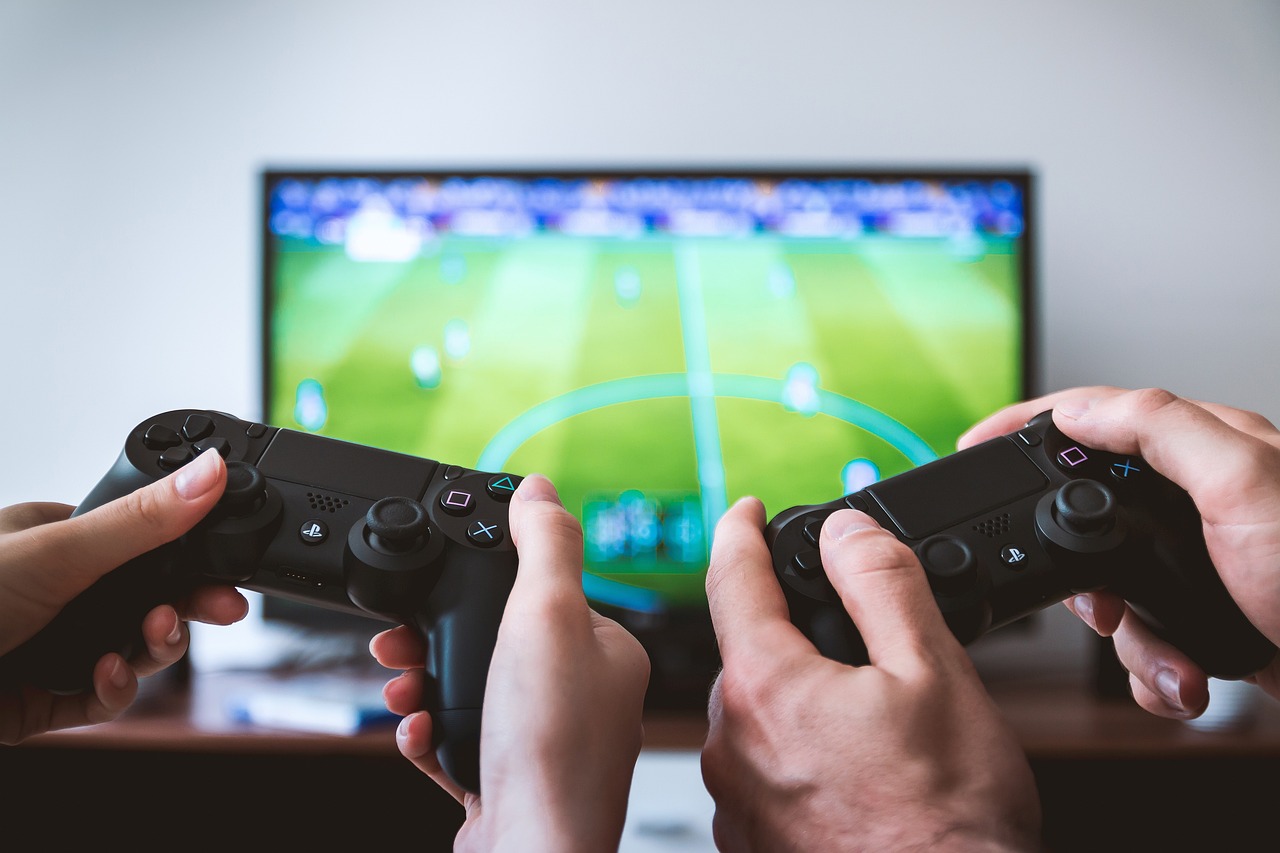 two sets of hands with controllers framed by a screen