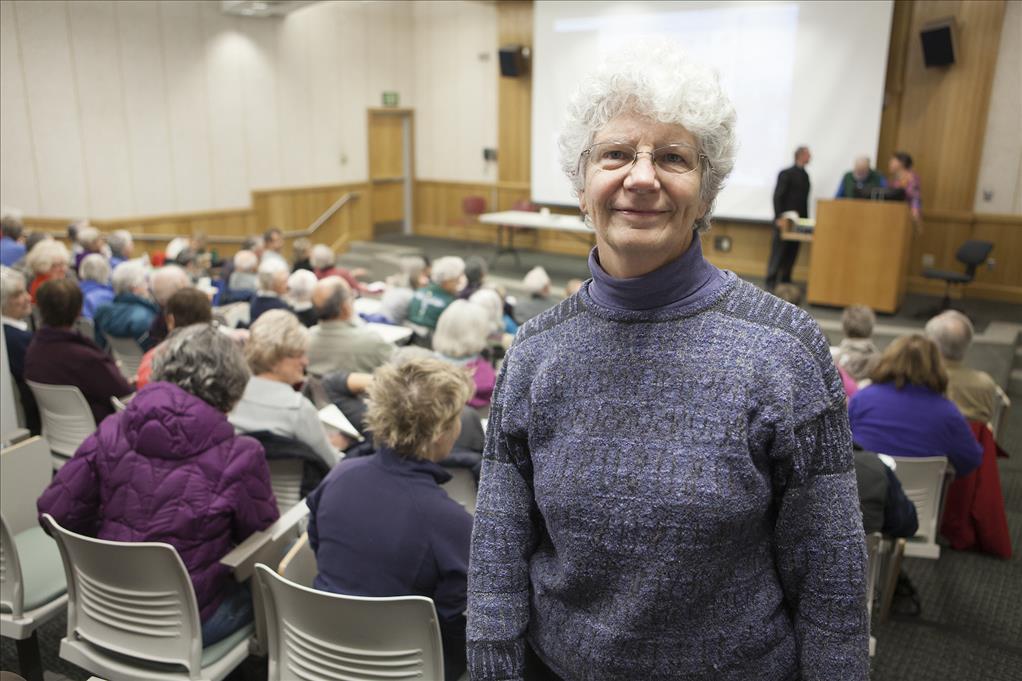 a woman with short white hair stands in a classroom auditorium