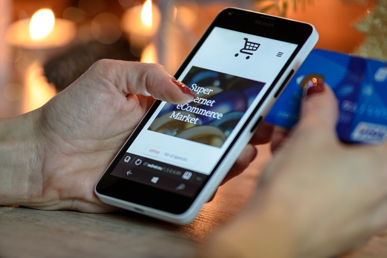 an iphone in a hand, the screen shows someone shopping