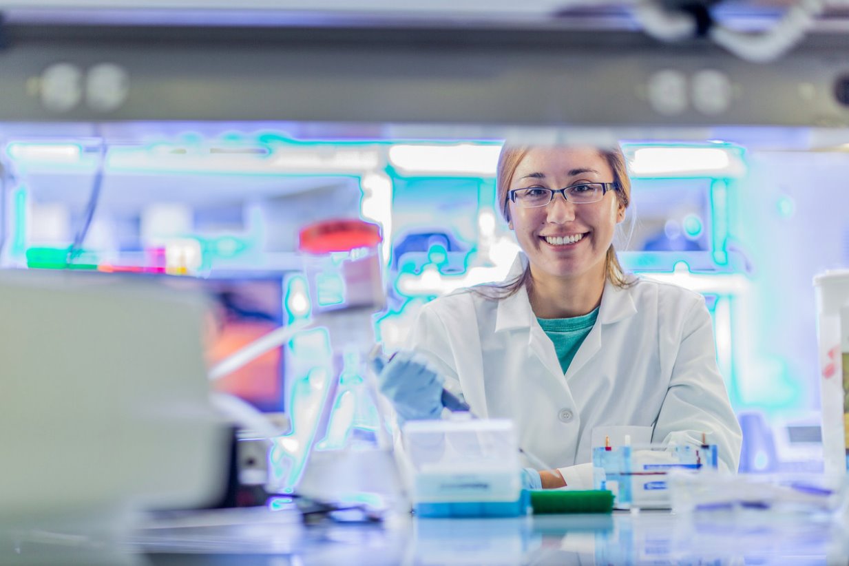 a female scientist smiles as she sits in a lab