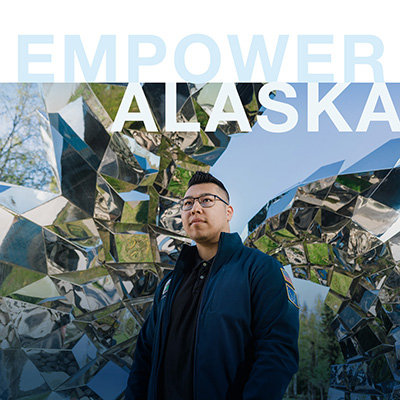 Student standing by art sculpture - text says Empower Alaska