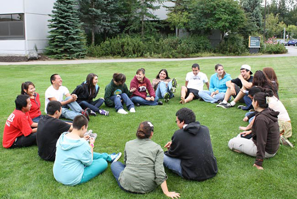 Students seated in a circle on the lawn at UAA