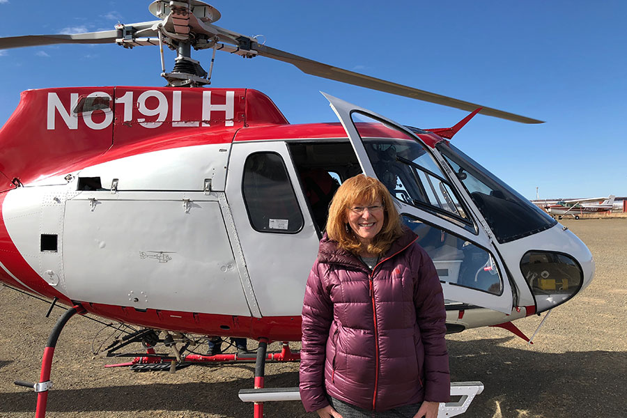 A mentor stands outside of a helicopter