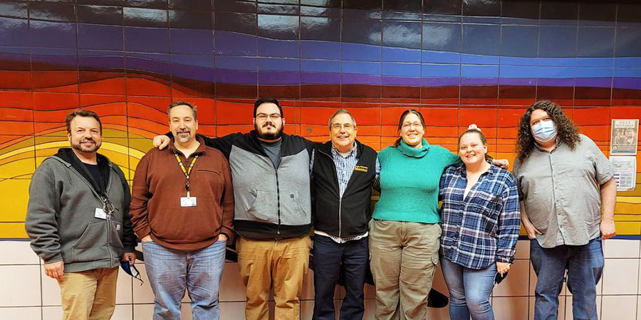 ASMP mentor group photo with several teaches in front of a colorful tile mural wall