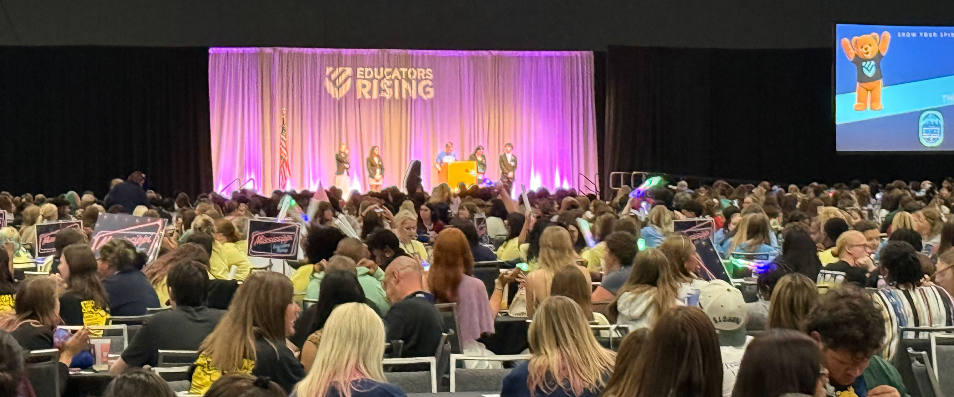 Educators Rising national conference attendees seated in a convention center hall facing a stage with speakers