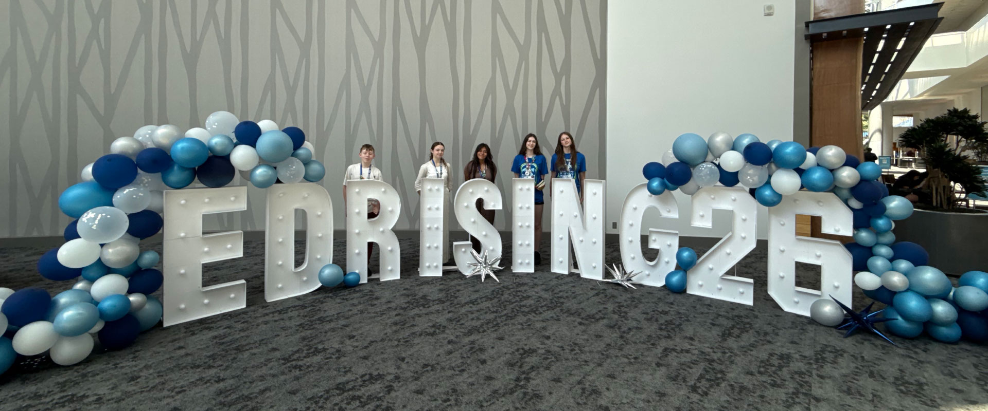 Educators Rising Alaska students stand behind an EdRising26 light and balloon display at the national conference
