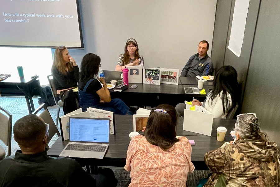Teachers communicating around two tables