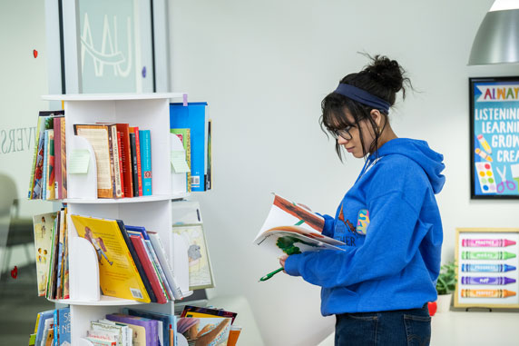 A student reviews books in the UAA library