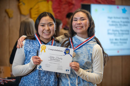 Students on stage holding certificates