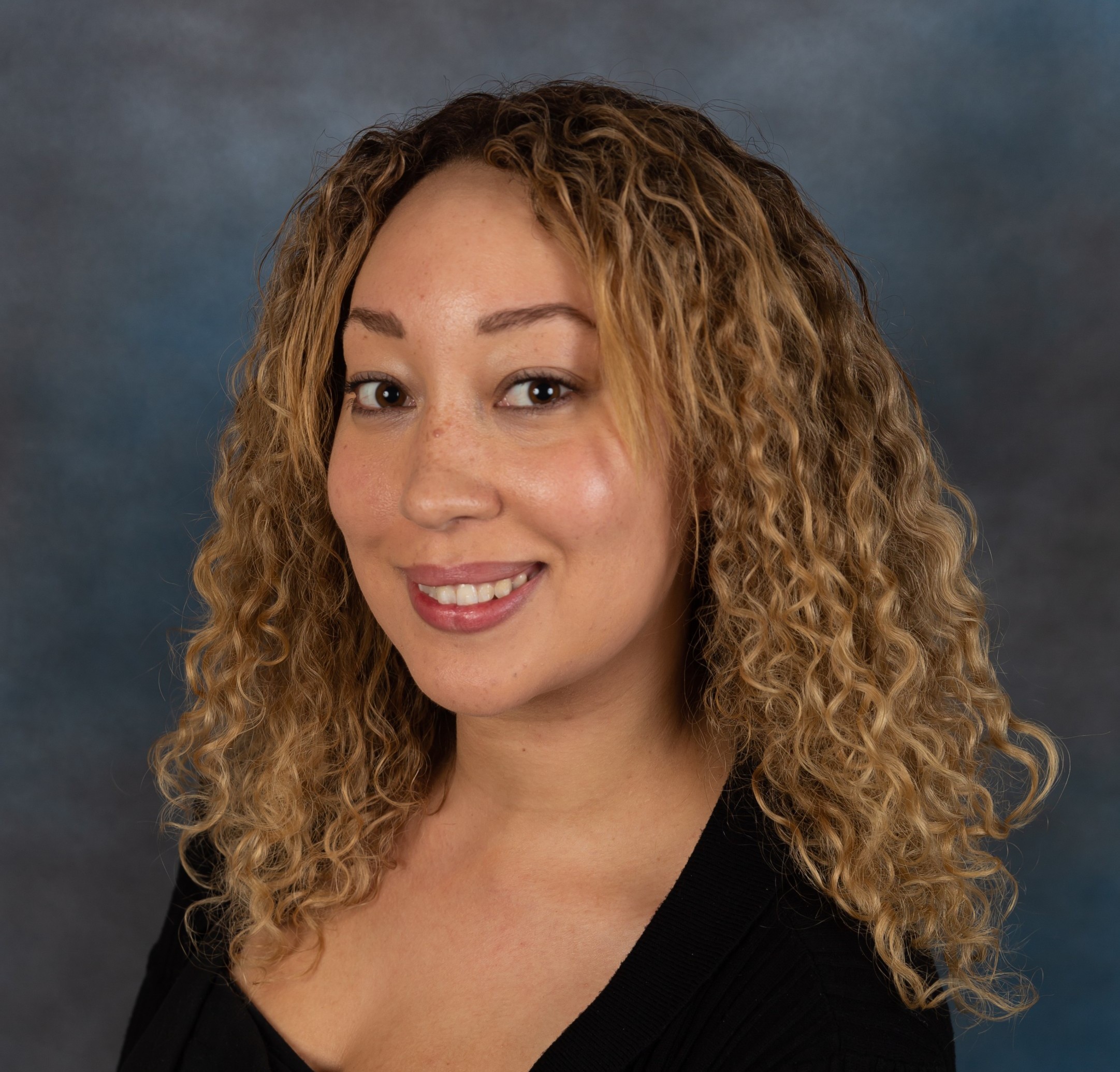 headshot picture of Stasia Craddick - curly brown hair and black dress