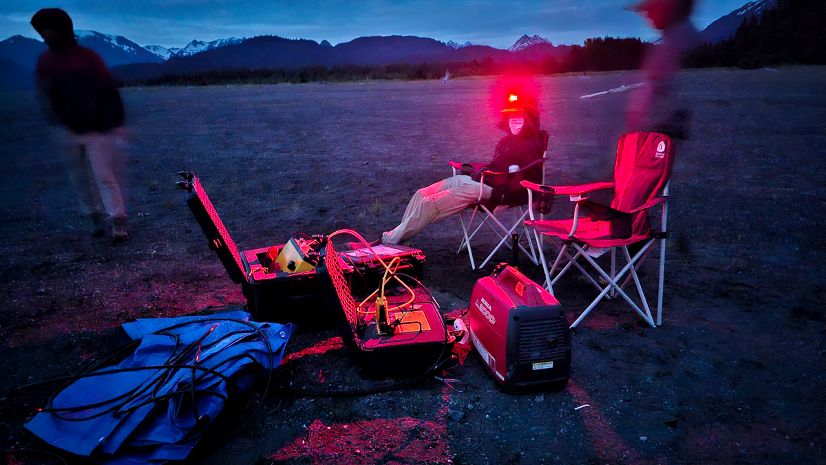 A night scene of hydrologists conducting a survey on a beach.