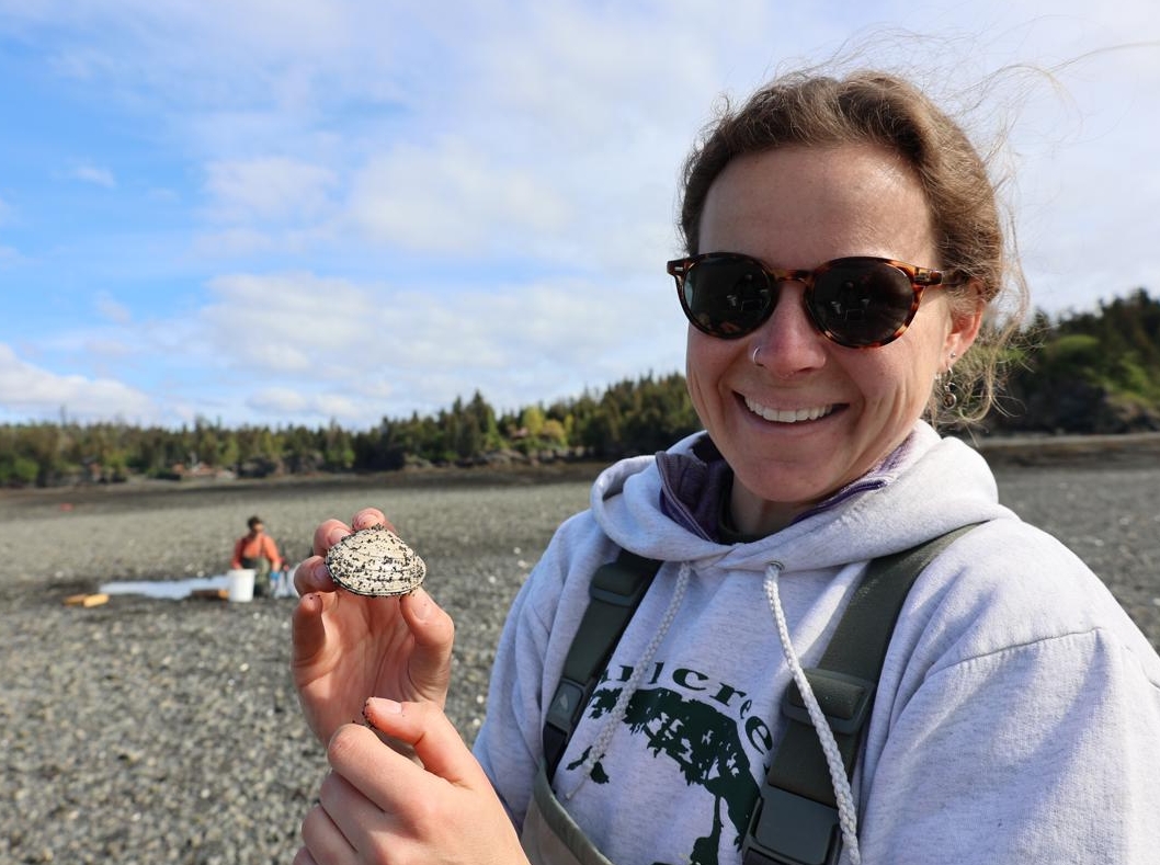 UAF graduate student Hannah Gerrish holds up a butter clam while sampling at the China Poot site in Kachemak Bay.
