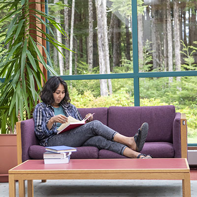 UAS student in library on coach in front of windows