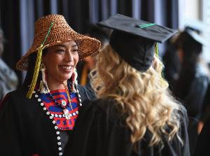 Graduating students wearing Tlingit hat and mortarboard