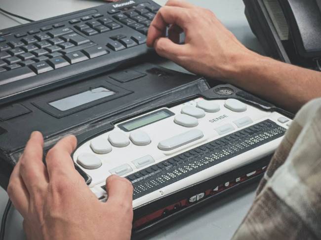 A view of two hands using a braille typewriter