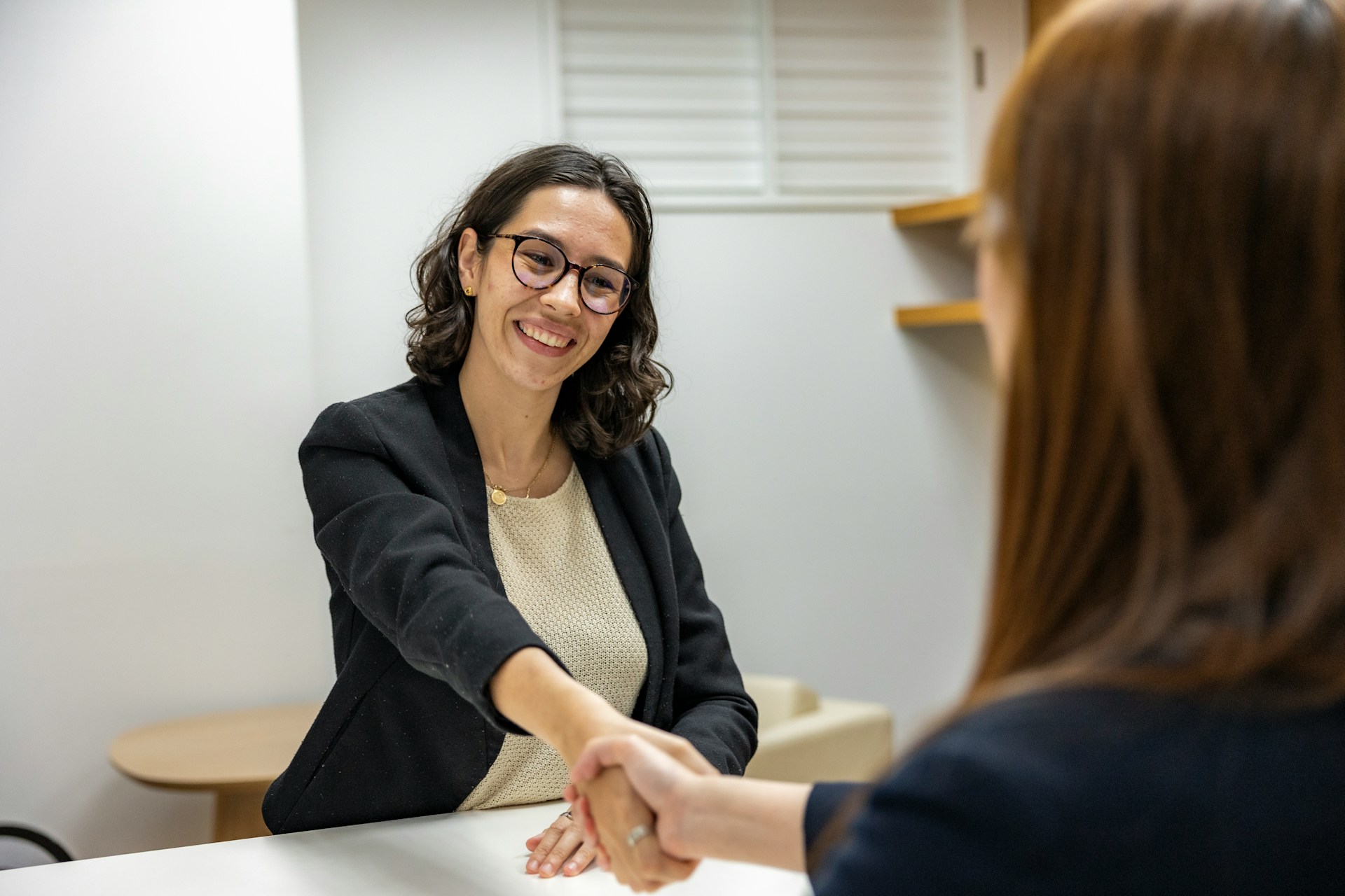 Two women shaking hands in an office setting