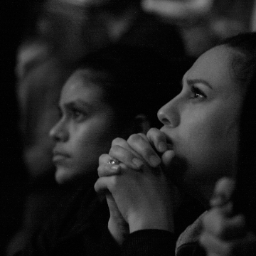 Woman resting chin on hands in a dark room