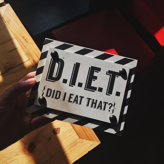 Hand Holding Diet Sign Over Table