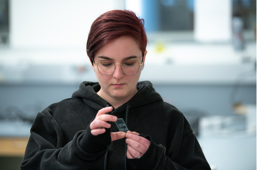 a woman with short hair looks down at a fingerprint glass in her hands