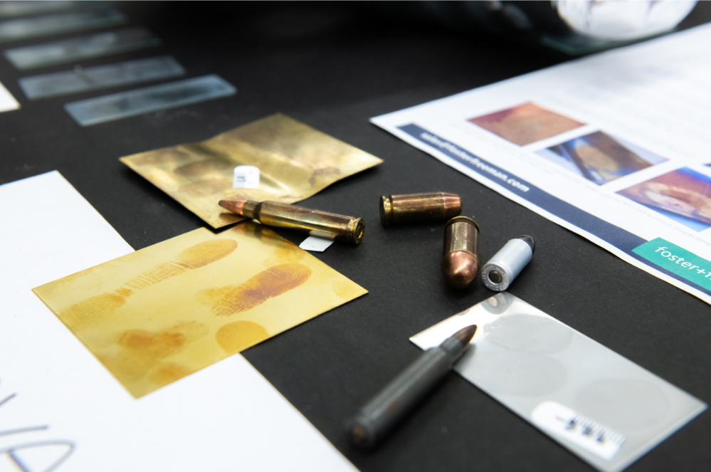 bullets and fingerprints on paper sit on a black table