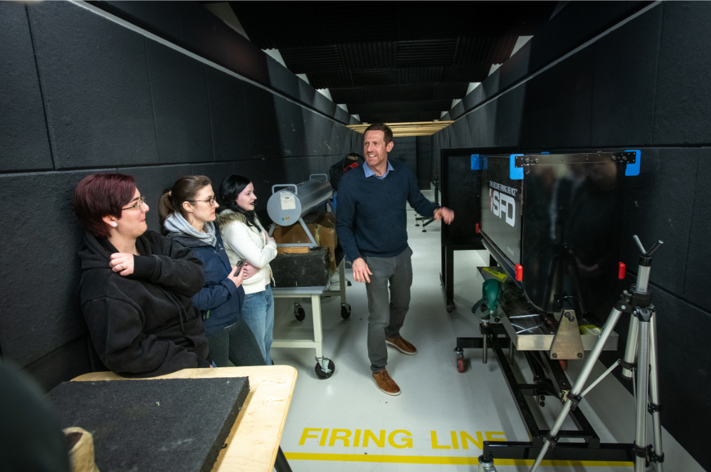 David Kanaris speaks to students in front of a tv screen