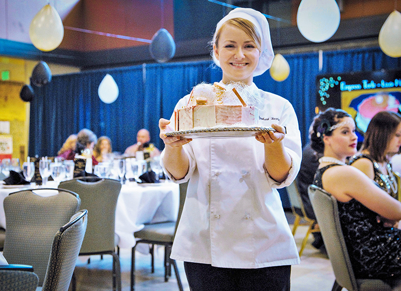 "Lizzie" Hartman in chef gear holding cake