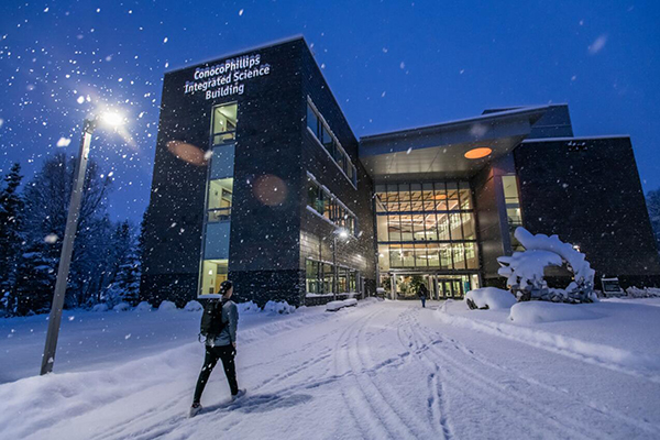 a student makes his way into a UAF building in winter darkness