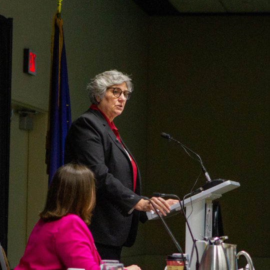 President Pat Pitney stands at the podium, delivering the 2024 State of the University at the Anchorage Chamber of Commerce.