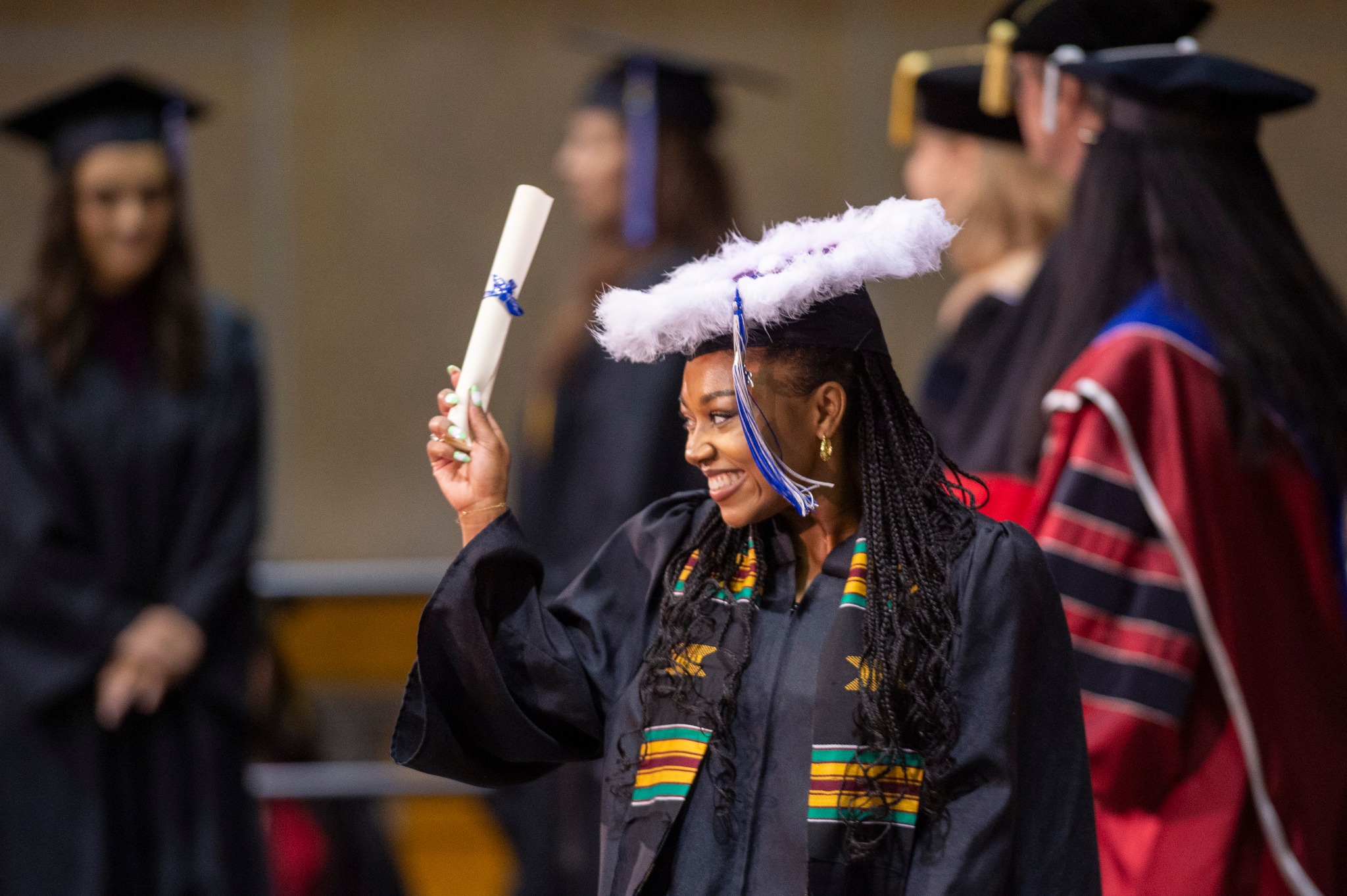 a grad holds her diploma up as she walks across the UAS stage