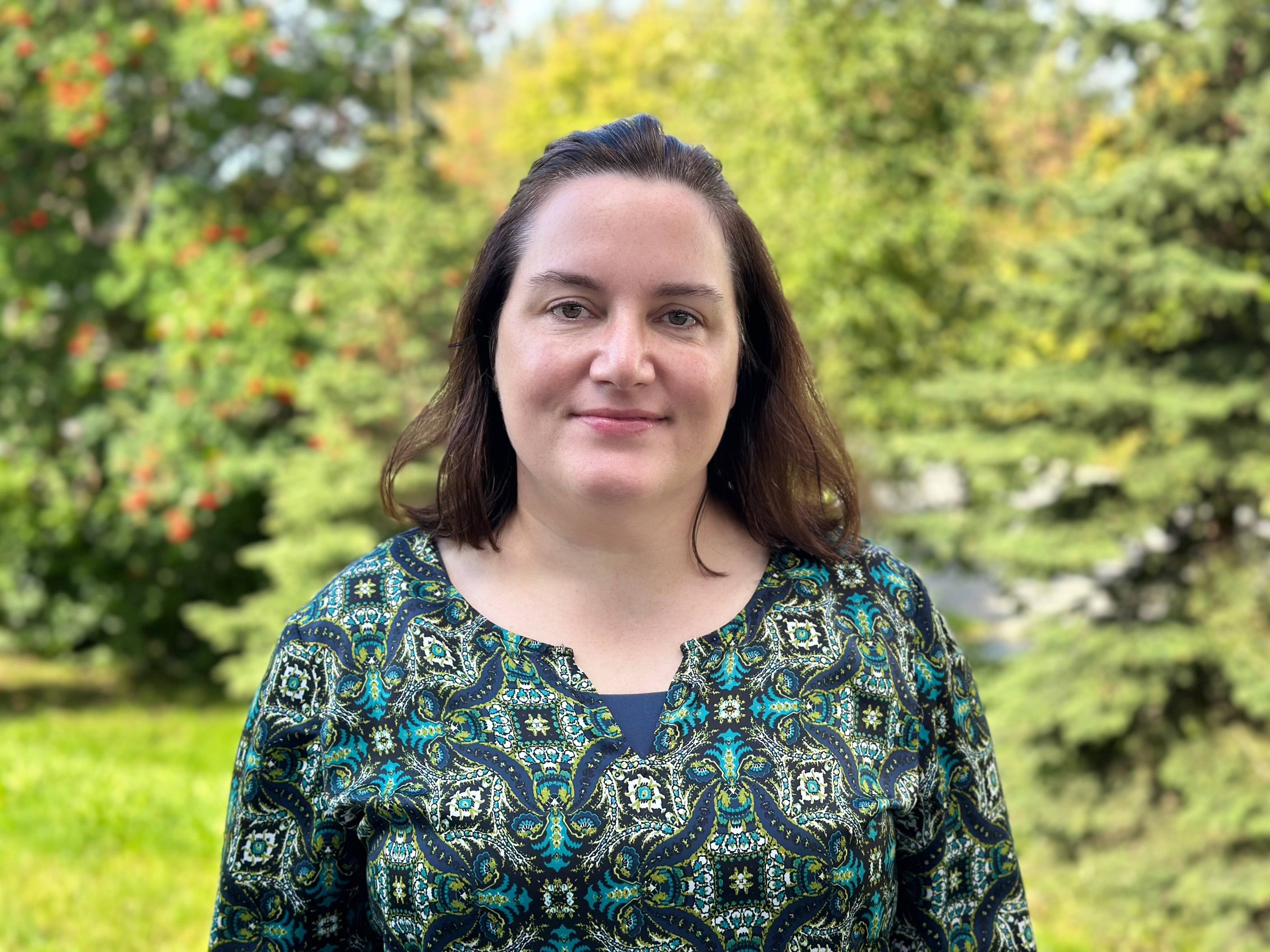 A woman with long brown hair and a green shirt in summer