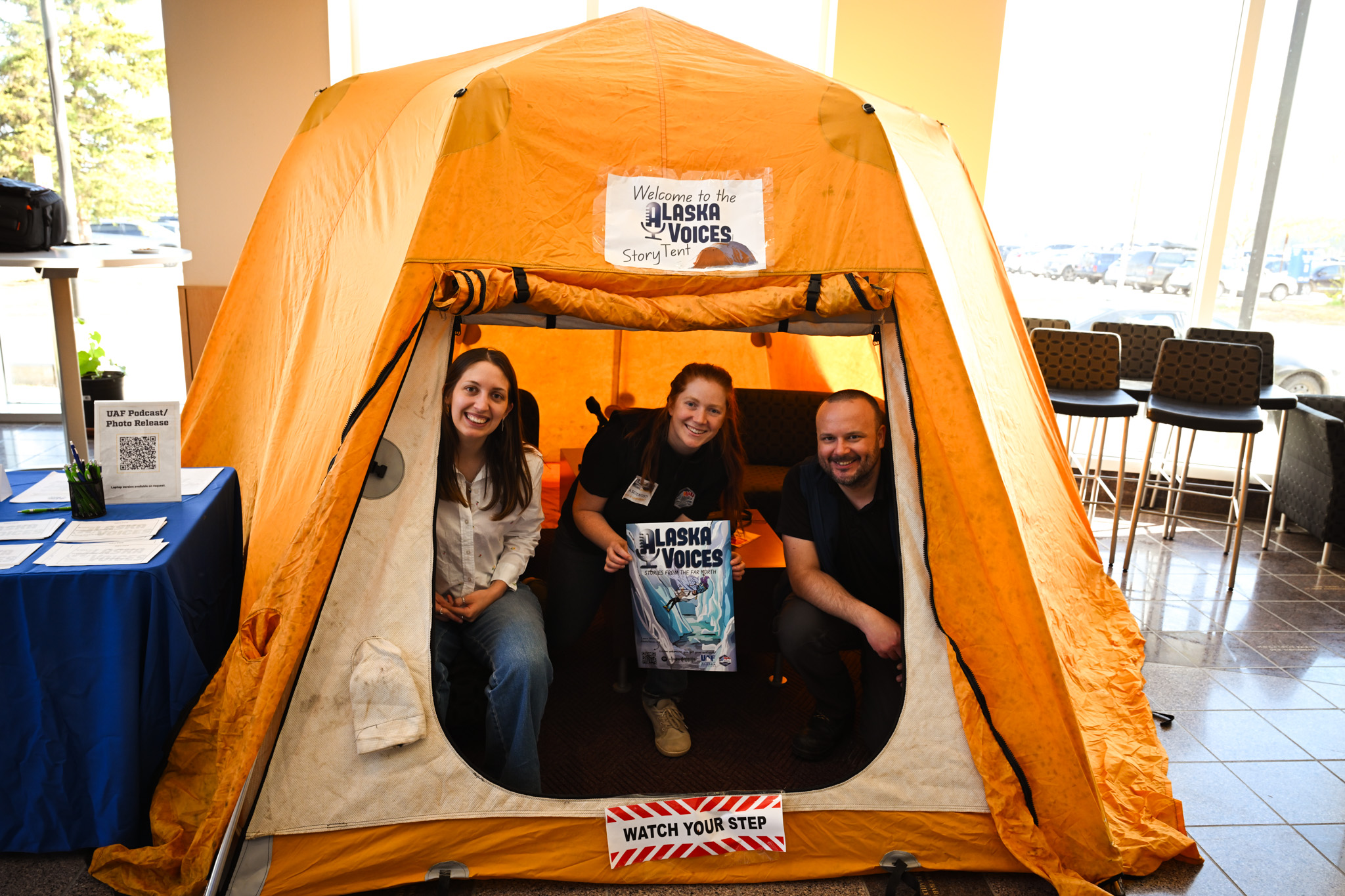 A group of three people sit in an orange tent