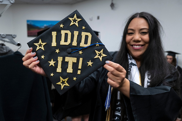 a graduate holds up her cap which reads 