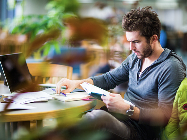 A student looks over open textbooks in the library