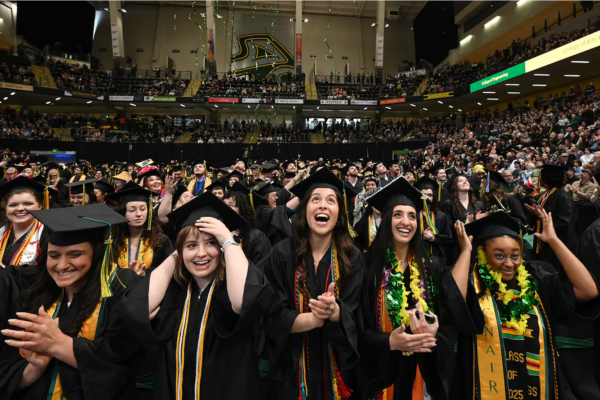 UAA graduates stand as the graduates toss their caps in the air
