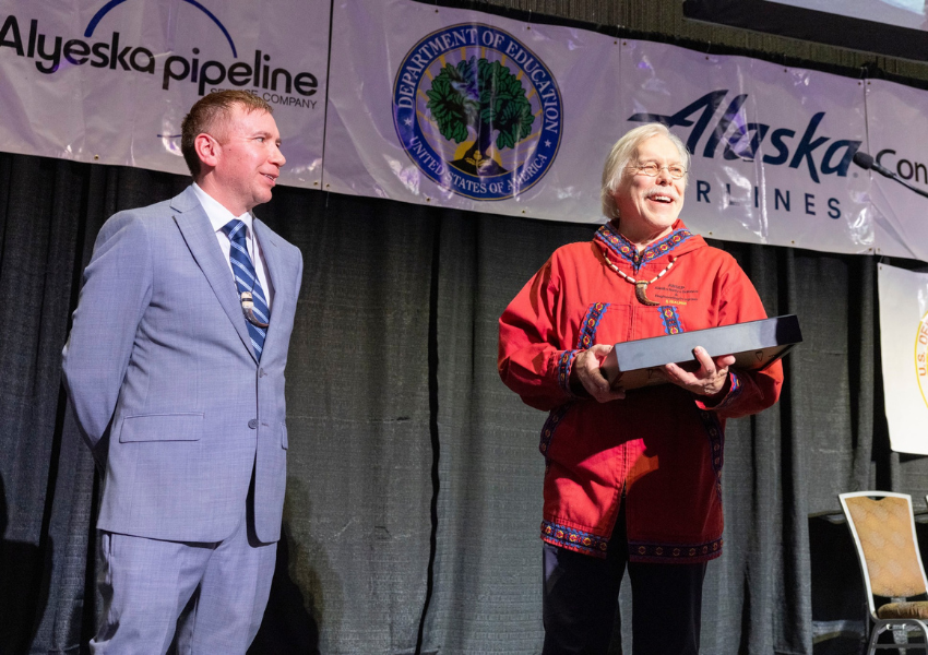 ANSEP founder Herb Schroeder receives recognition on stage at the 31st annual ANSEP celebration, with partner banners for Alyeska Pipeline, the U.S. Department of Education and Alaska Airlines visible in the background.