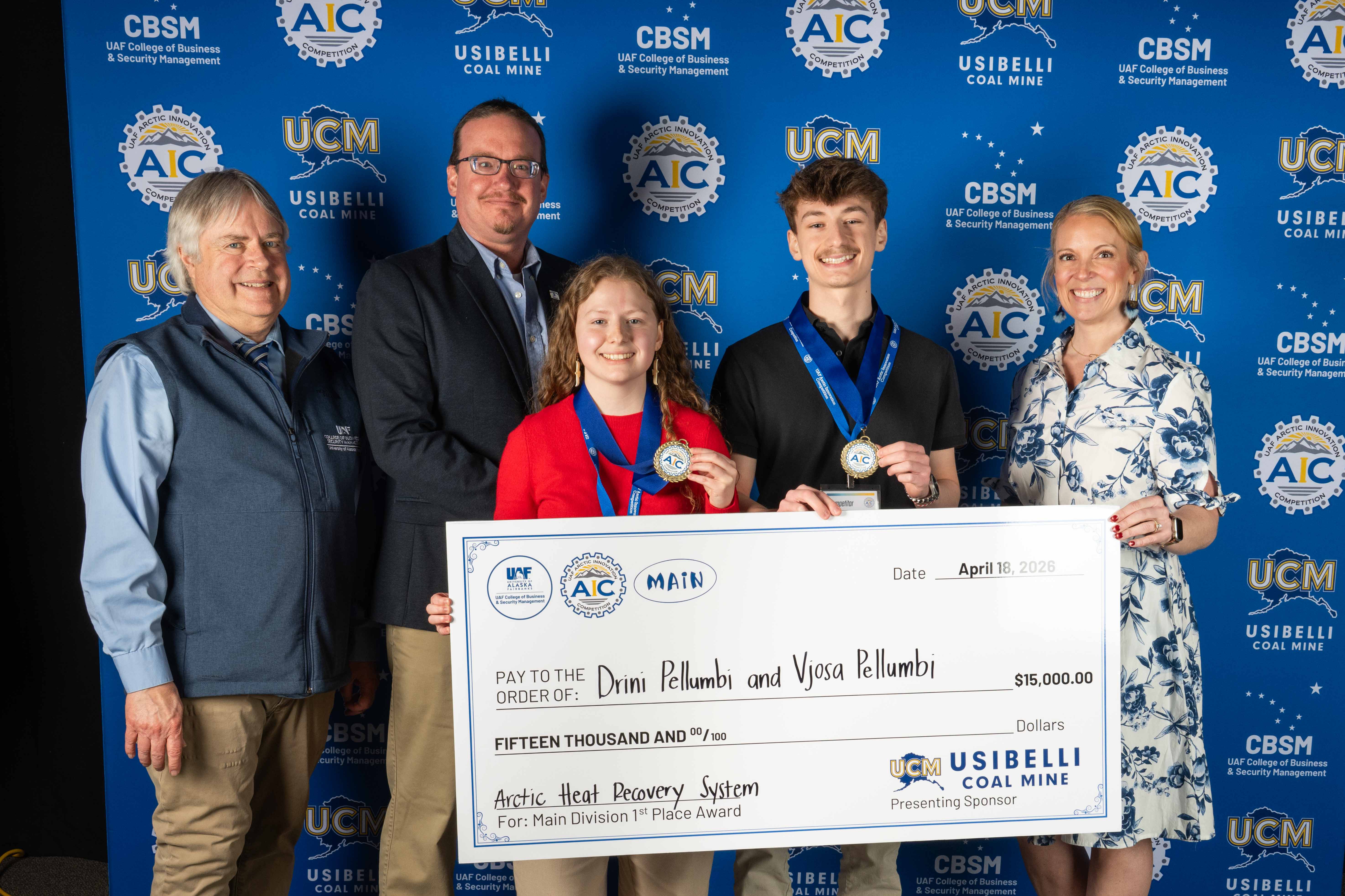 Vjosa and Drini Pellumbi hold an oversized $15,000 check from Usibelli Coal Mine and display their gold medals at the 2026 Arctic Innovation Competition in Fairbanks on April 18, 2026. They are joined by UAF College of Business and Security Management Associate Dean Mark Hermann, Usibelli engineer Justin Seavey and Usibelli Vice President of Public Relations Lisa Putnam.