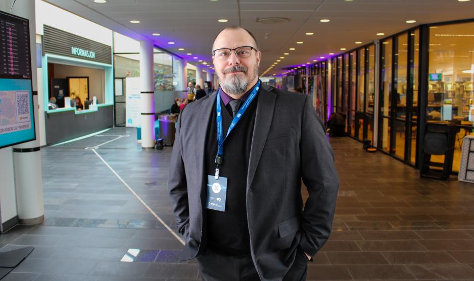 Dr. Troy Bouffard standing in Norway, with badge, suit and glasses on