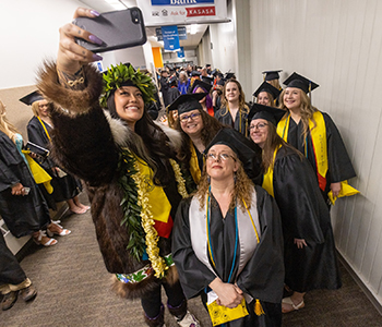 Graduates take a selfi in the hallway while lined up for commencement