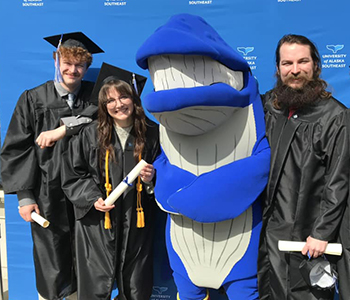 UAS graduates pose for a photo with the mascot Spike
