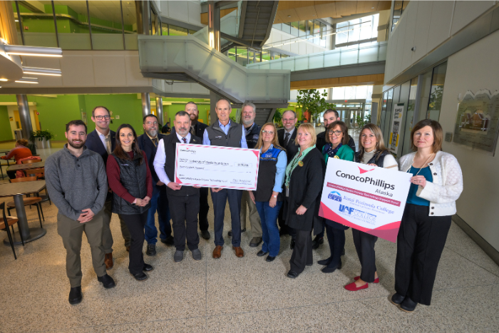 a group of people pose with a giant check in hand