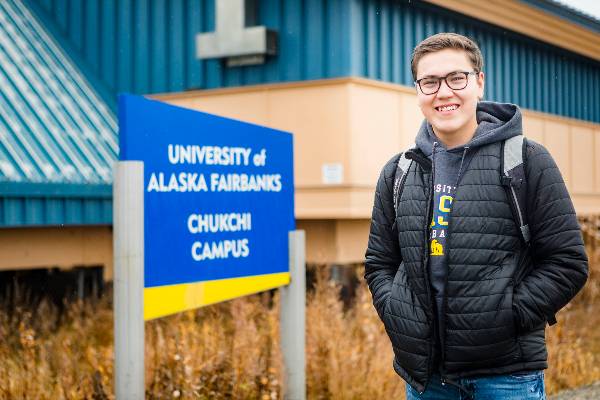 student stands in front of Chukchi Campus sign