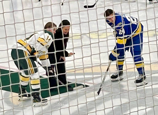 Ella Goss dropping puck with hockey players at center ice