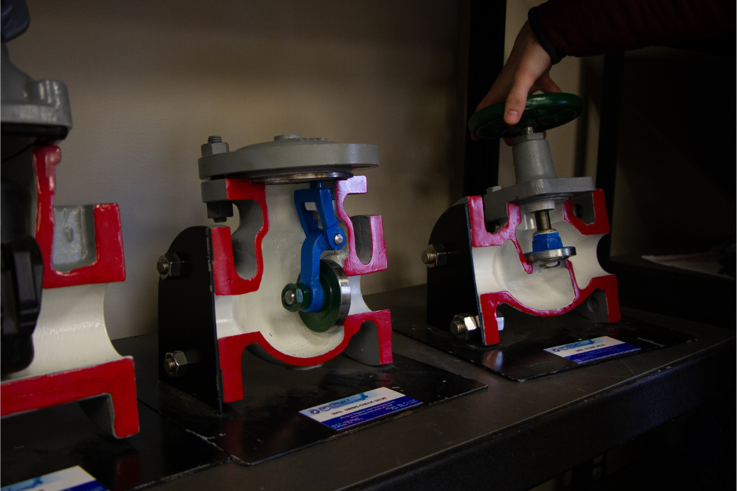 Close-up of cross-section industrial valve training models on a lab table at Kenai Peninsula College, showing internal components used for process technology instruction.