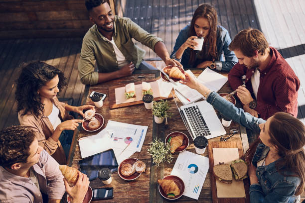 A business lunch meeting - group with computers sitting around a table with food