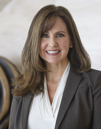 A woman with long brown hair and suit smiling