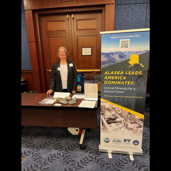 ACMC Director Lee Ann Munk stands at an information table with mineral samples and a display banner promoting the Alaska Critical Mineral Accelerator in Washington, D.C.