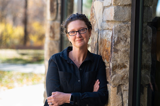 A woman leans against a brick building