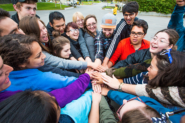 A group of students put their hands into a circle